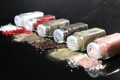 Photo of Different spices and glass jars on mirror surface, closeup