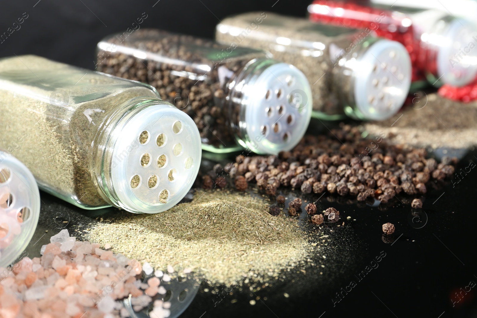 Photo of Different spices and glass jars on mirror surface, closeup