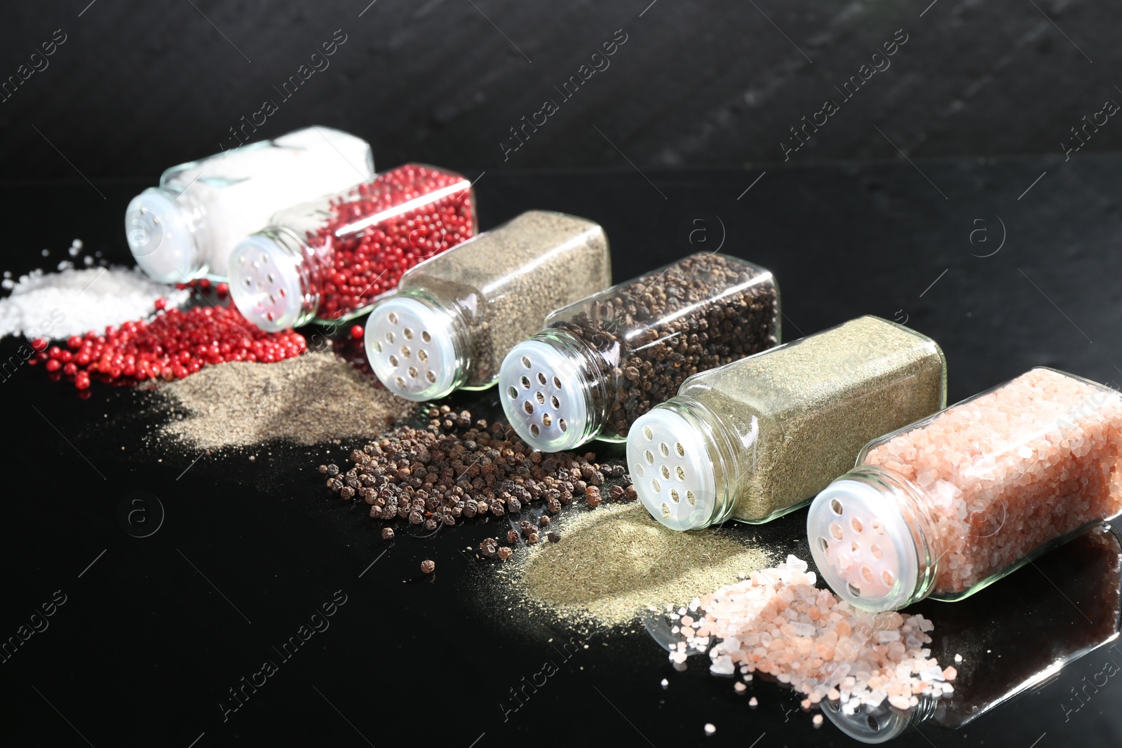 Photo of Different spices and glass jars on mirror surface