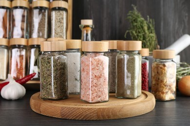 Photo of Different spices and glass jars on grey wooden table, closeup