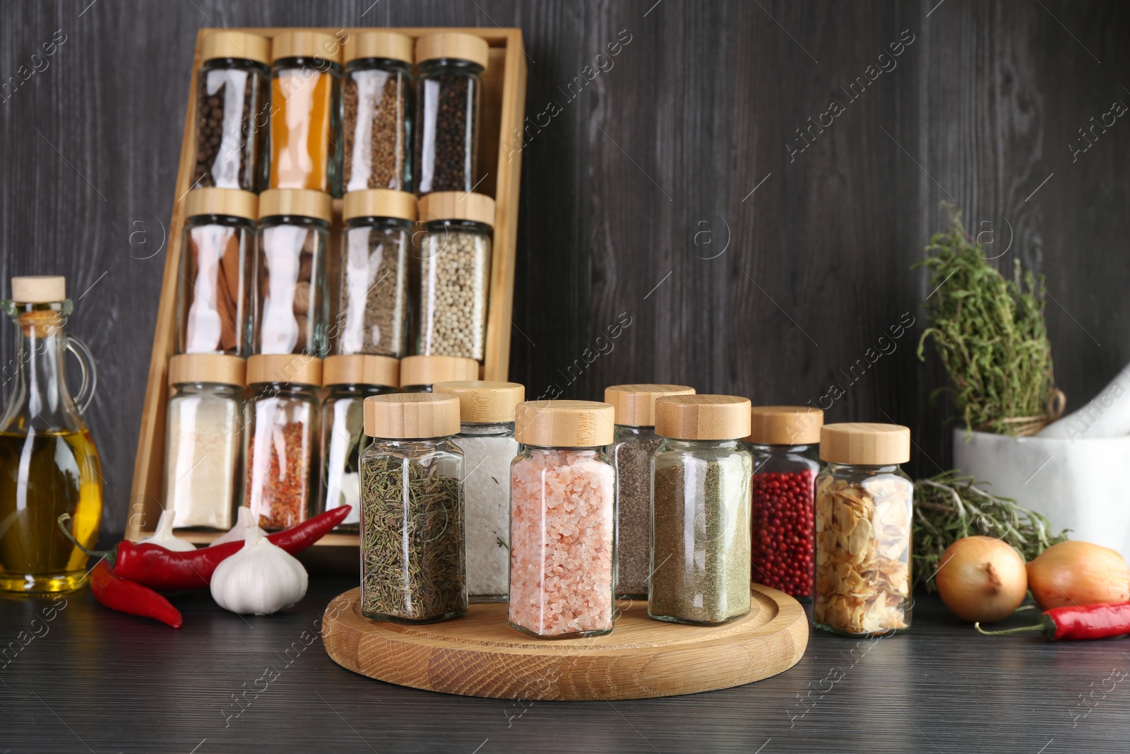 Different spices and glass jars on grey wooden table Photo of Different spices and glass jars on grey wooden table