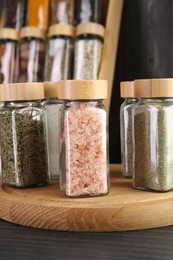 Photo of Different spices in glass jars on grey wooden table, closeup