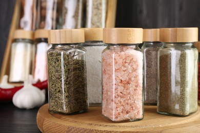 Photo of Different spices in glass jars on grey wooden table, closeup