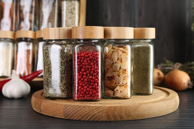 Photo of Different spices in glass jars on grey wooden table, closeup