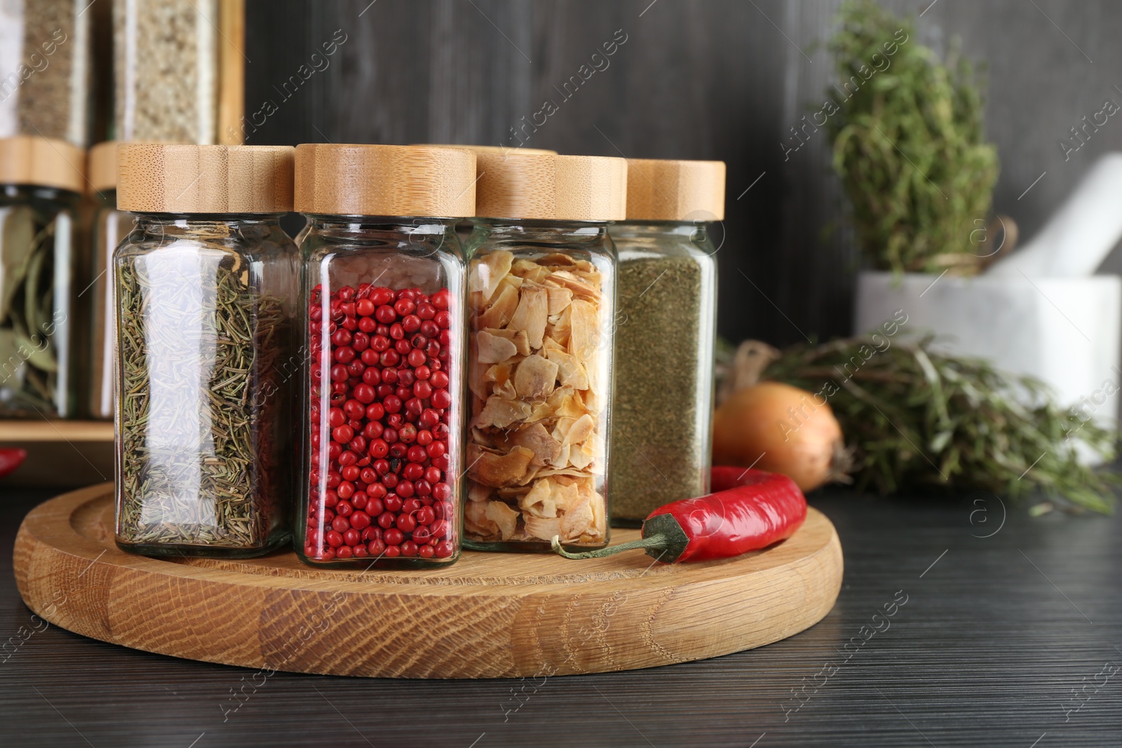 Different spices in glass jars on grey wooden table, closeup Photo of Different spices in glass jars on grey wooden table, closeup