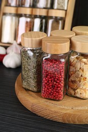 Photo of Different spices in glass jars on grey wooden table, closeup