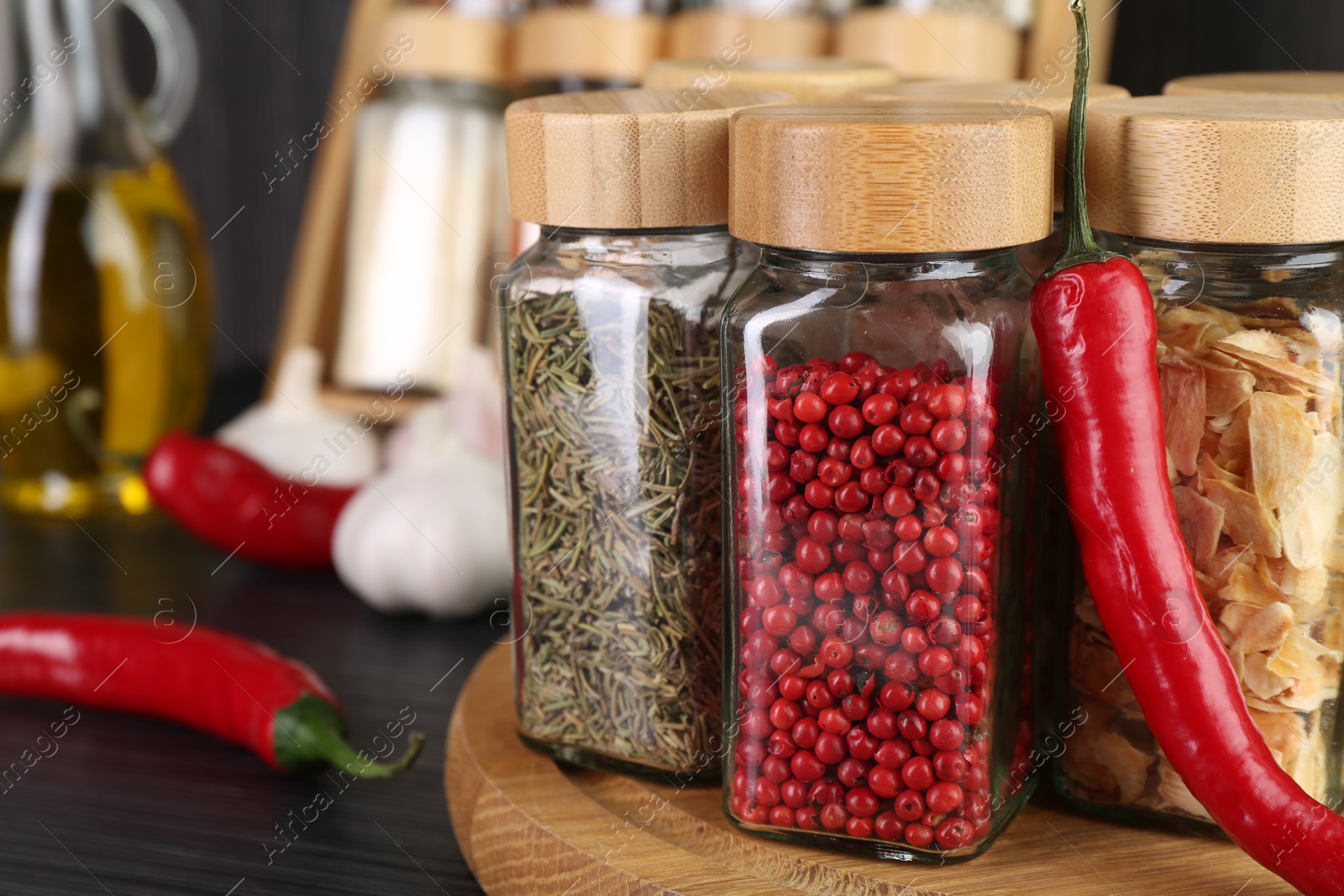 Different spices in glass jars and chili pepper on grey wooden table, closeup Photo of Different spices in glass jars and chili pepper on grey wooden table, closeup