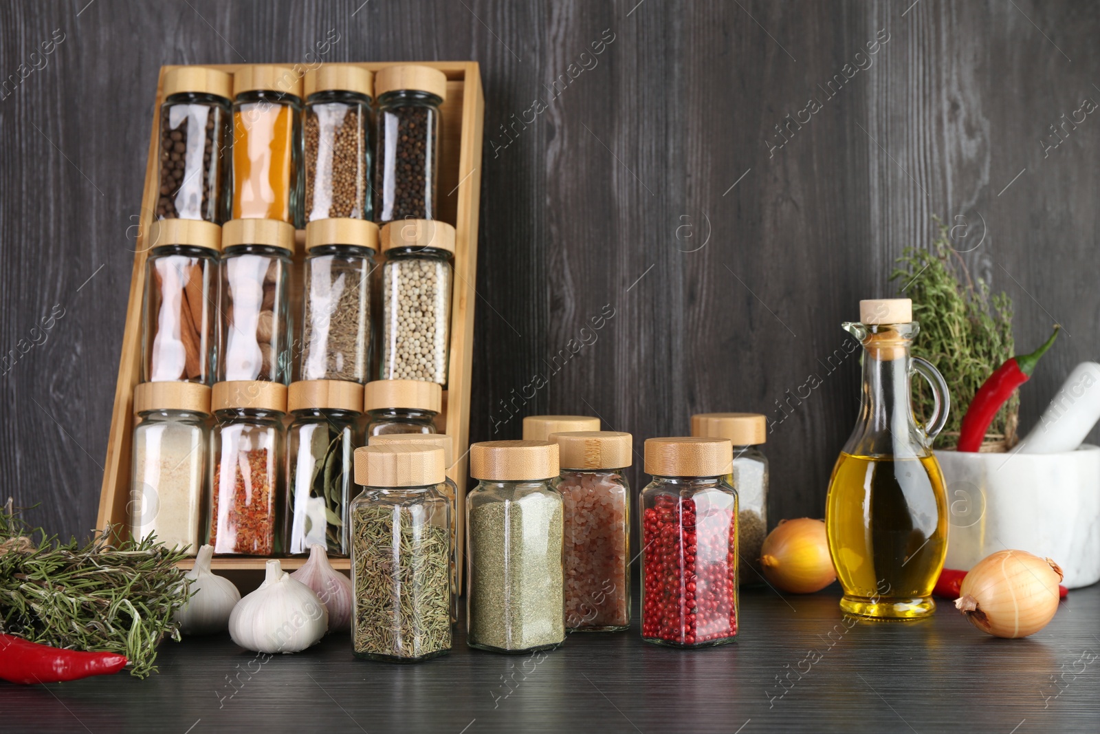 Different spices and glass jars on grey wooden table Photo of Different spices and glass jars on grey wooden table