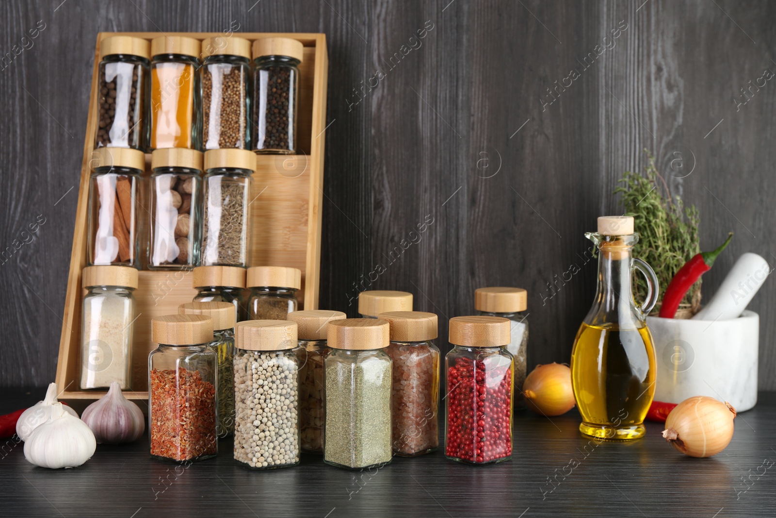 Different spices and glass jars on grey wooden table Photo of Different spices and glass jars on grey wooden table