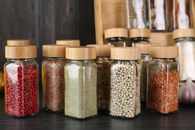 Photo of Different spices in glass jars on grey wooden table, closeup