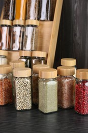 Photo of Different spices in glass jars on grey wooden table, closeup