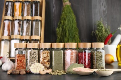 Photo of Different spices and glass jars on grey wooden table