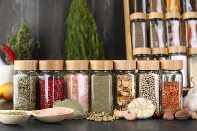 Photo of Different spices and glass jars on grey wooden table