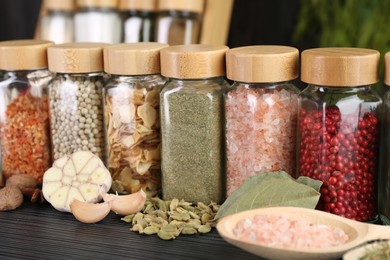 Photo of Different spices and glass jars on grey wooden table, closeup
