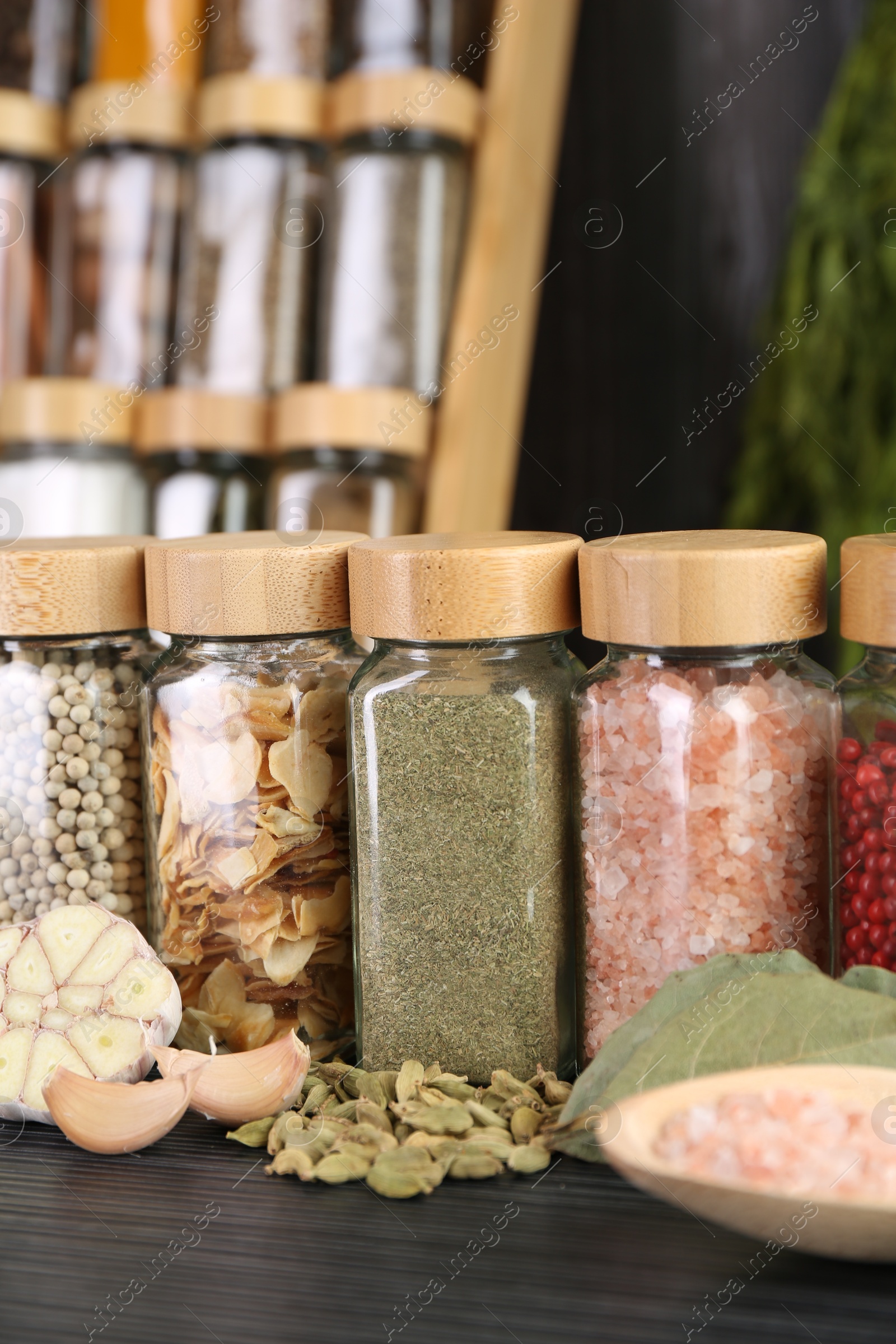 Photo of Different spices and glass jars on grey wooden table, closeup