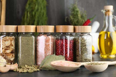 Photo of Different spices and glass jars on grey wooden table, closeup