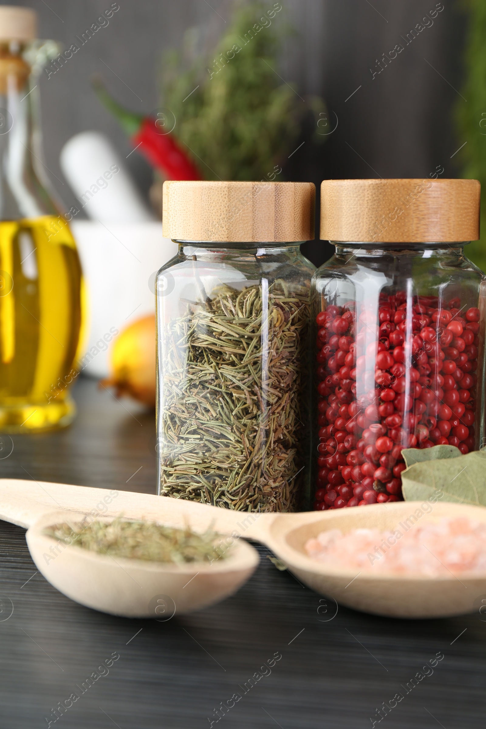 Different spices and glass jars on grey wooden table, closeup Photo of Different spices and glass jars on grey wooden table, closeup