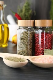 Photo of Different spices and glass jars on grey wooden table, closeup
