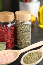 Photo of Different spices and glass jars on grey wooden table, closeup