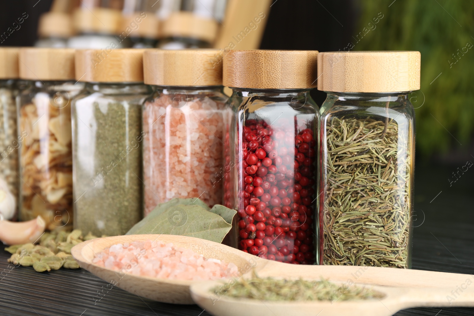 Different spices and glass jars on grey wooden table, closeup Photo of Different spices and glass jars on grey wooden table, closeup