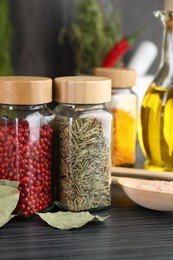Photo of Different spices and glass jars on grey wooden table, closeup