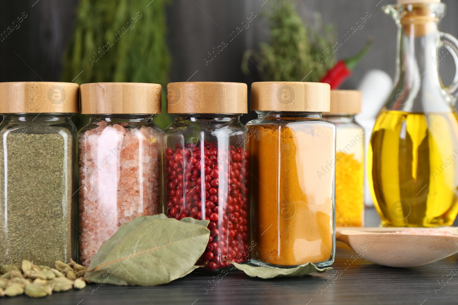 Different spices and glass jars on grey wooden table, closeup Photo of Different spices and glass jars on grey wooden table, closeup