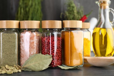 Photo of Different spices and glass jars on grey wooden table, closeup