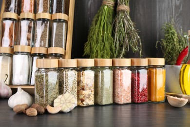 Photo of Different spices and glass jars on grey wooden table