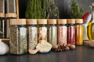 Photo of Different spices and glass jars on grey wooden table, closeup