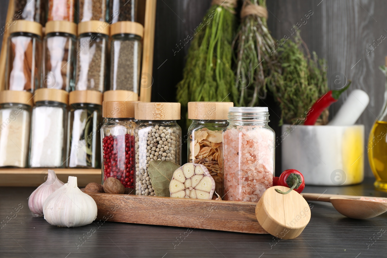 Photo of Different spices and glass jars on grey wooden table