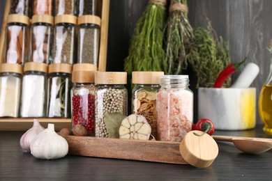 Photo of Different spices and glass jars on grey wooden table