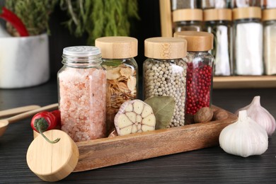 Photo of Different spices and glass jars on grey wooden table, closeup