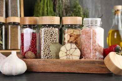 Photo of Different spices and glass jars on grey wooden table, closeup