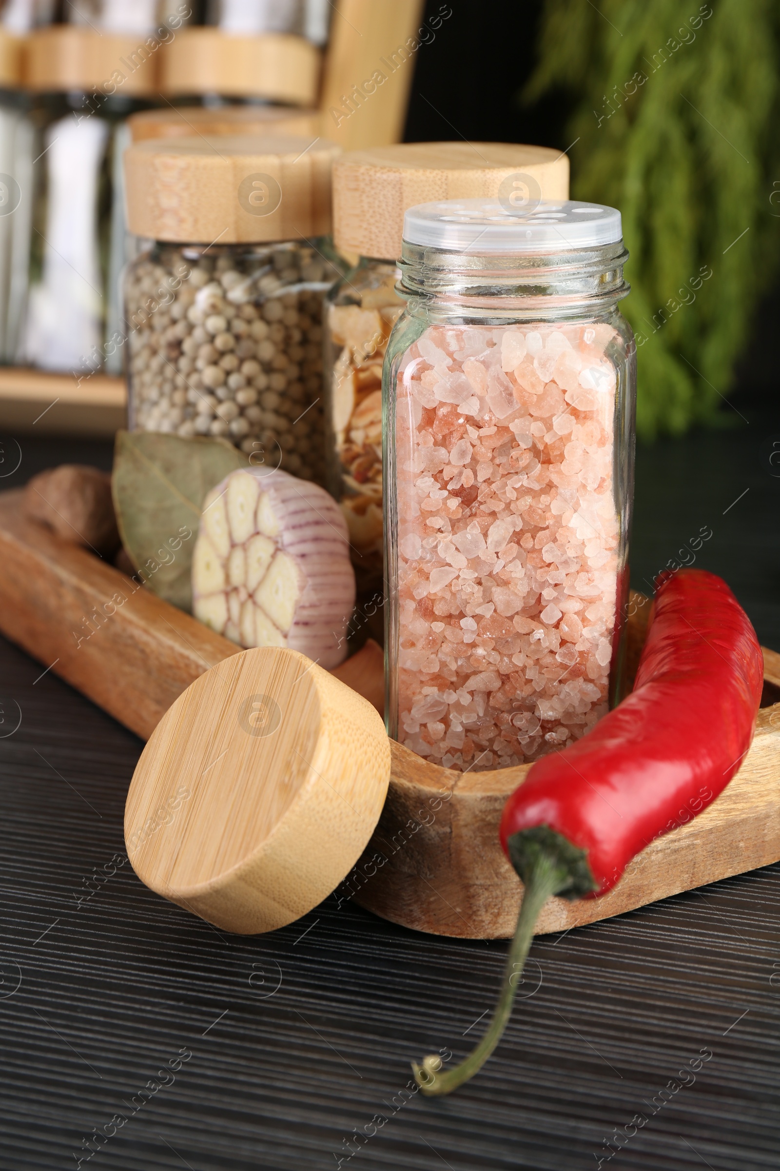Different spices and glass jars on grey wooden table, closeup Photo of Different spices and glass jars on grey wooden table, closeup