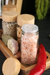 Photo of Different spices and glass jars on grey wooden table, closeup