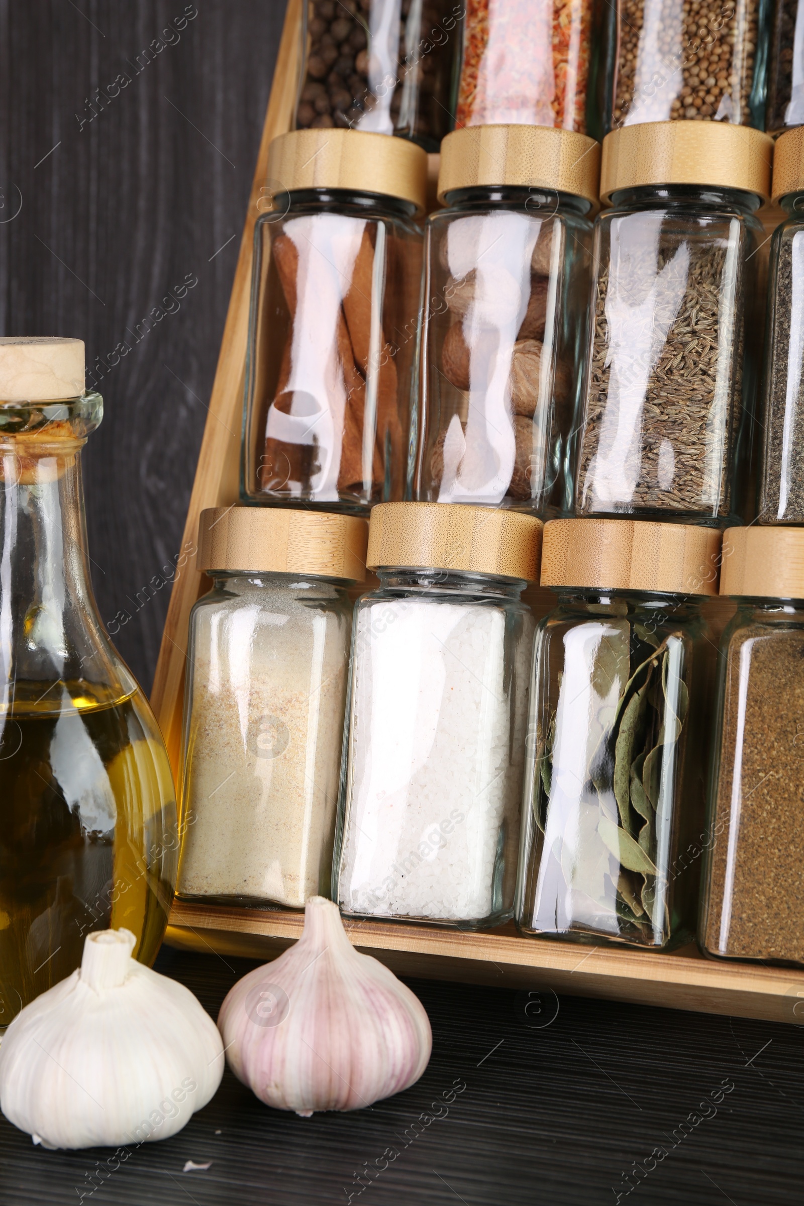 Photo of Set of different spices in glass jars on grey wooden table, closeup