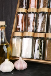 Photo of Set of different spices in glass jars on grey wooden table, closeup