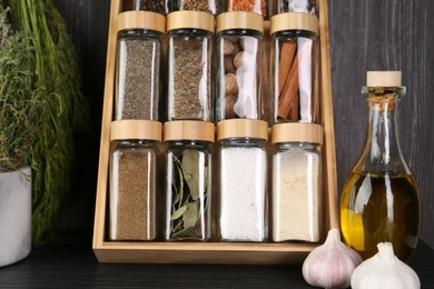 Photo of Set of different spices in glass jars on grey wooden table, closeup