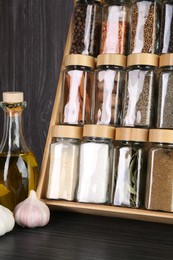 Photo of Set of different spices in glass jars on grey wooden table, closeup