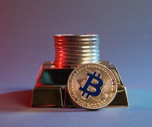 Photo of Bitcoins and gold bars on color background in red light, closeup