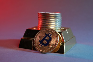 Photo of Bitcoins and gold bars on color background in red light, closeup