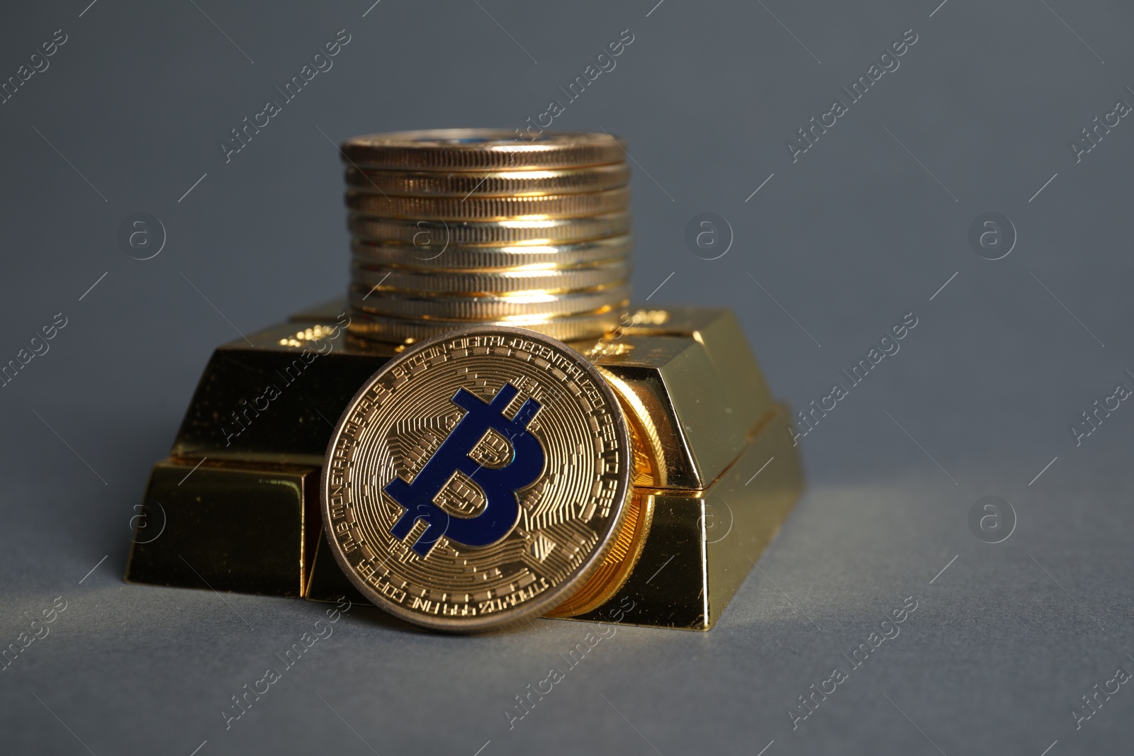 Photo of Bitcoins and gold bars on grey background, closeup