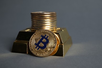 Photo of Bitcoins and gold bars on grey background, closeup