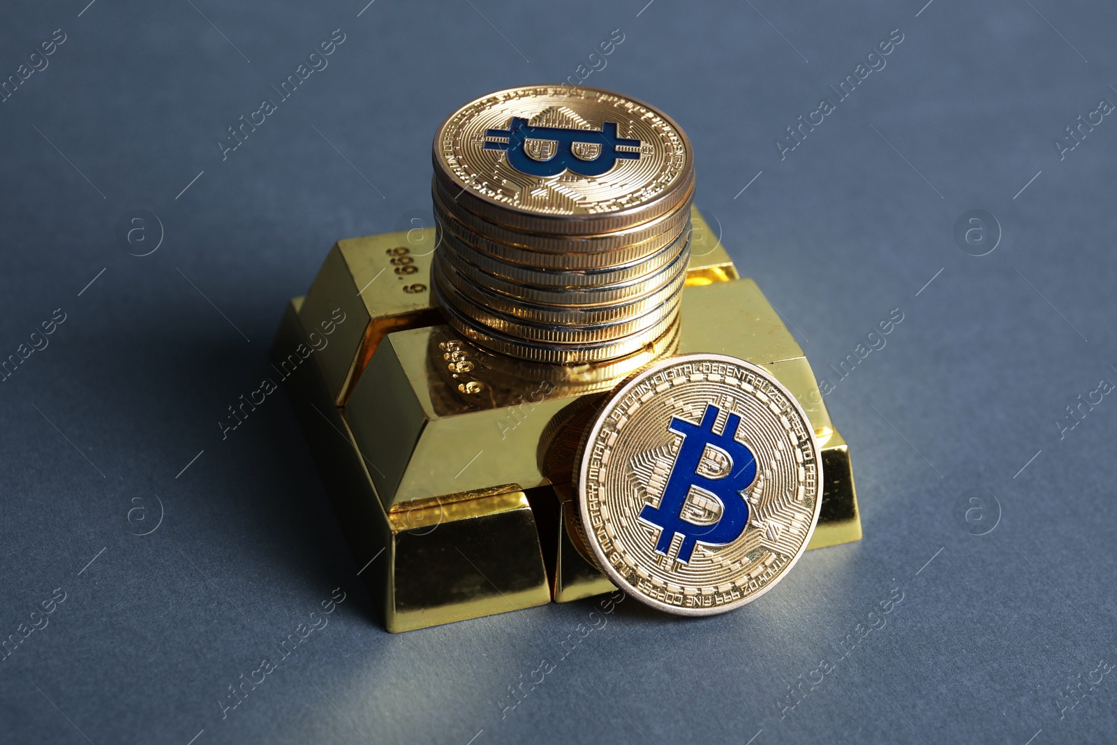 Photo of Bitcoins and gold bars on grey background, closeup