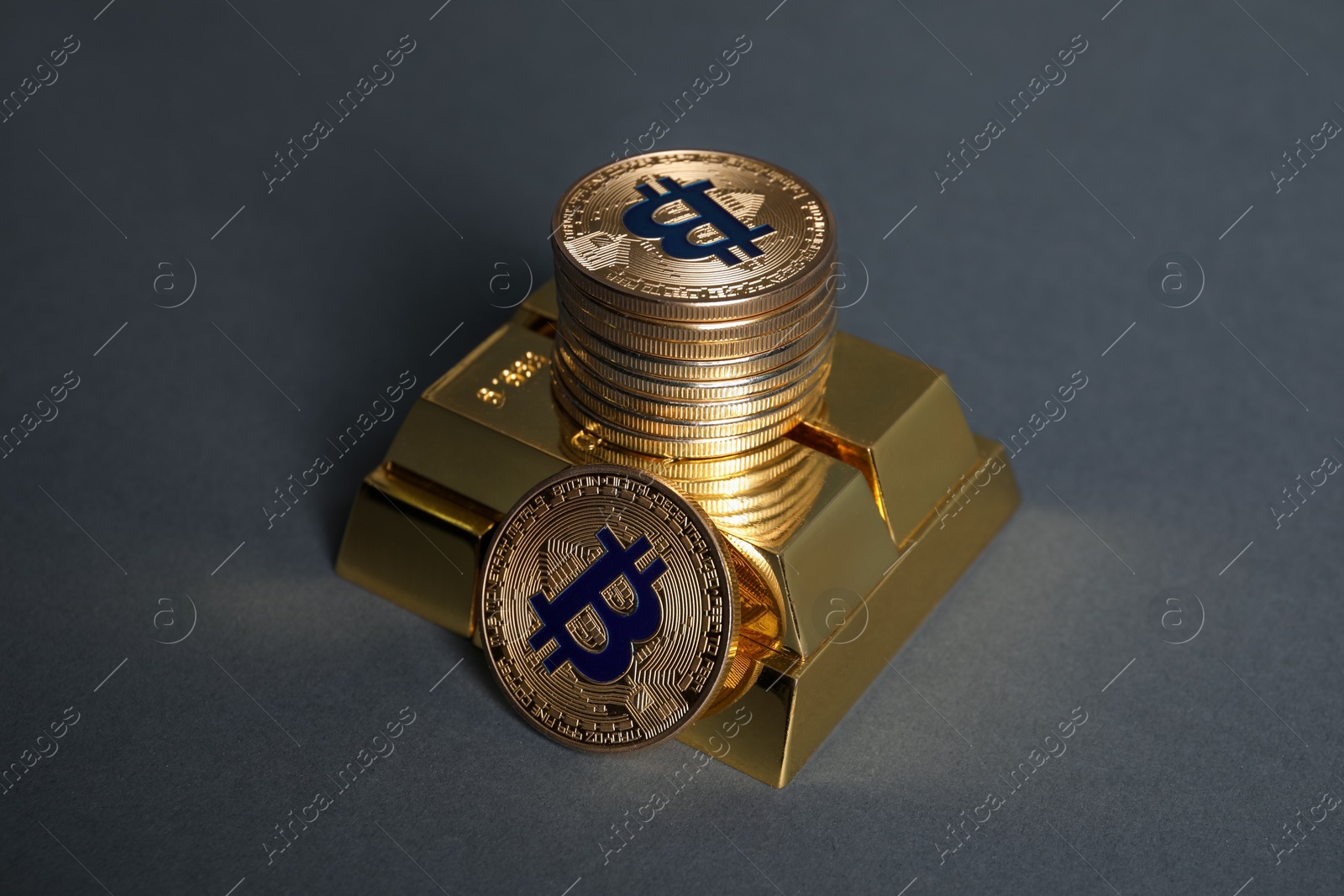 Photo of Bitcoins and gold bars on grey background, closeup
