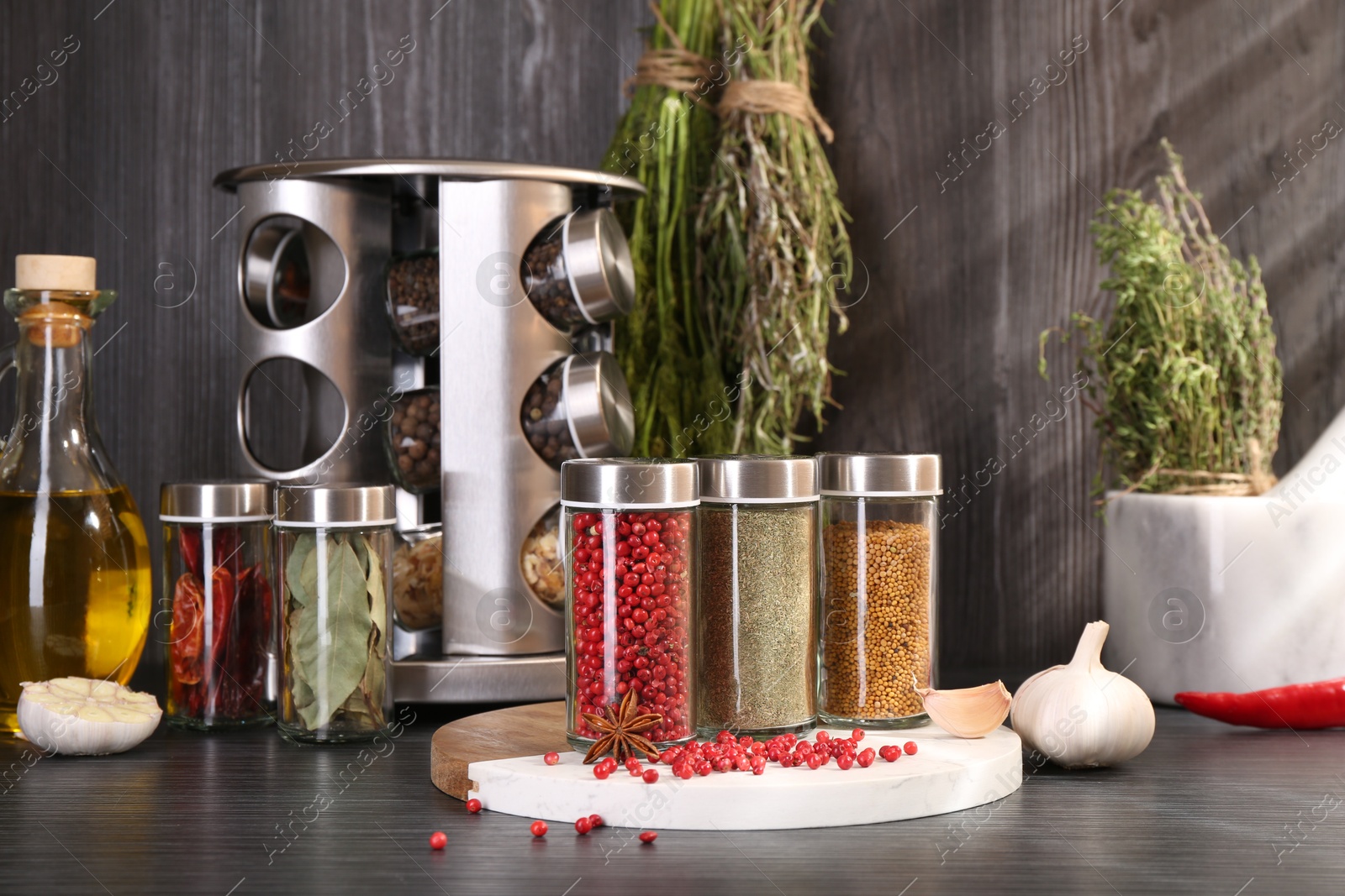 Different spices and glass jars on grey wooden table Photo of Different spices and glass jars on grey wooden table