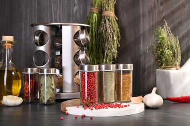Photo of Different spices and glass jars on grey wooden table