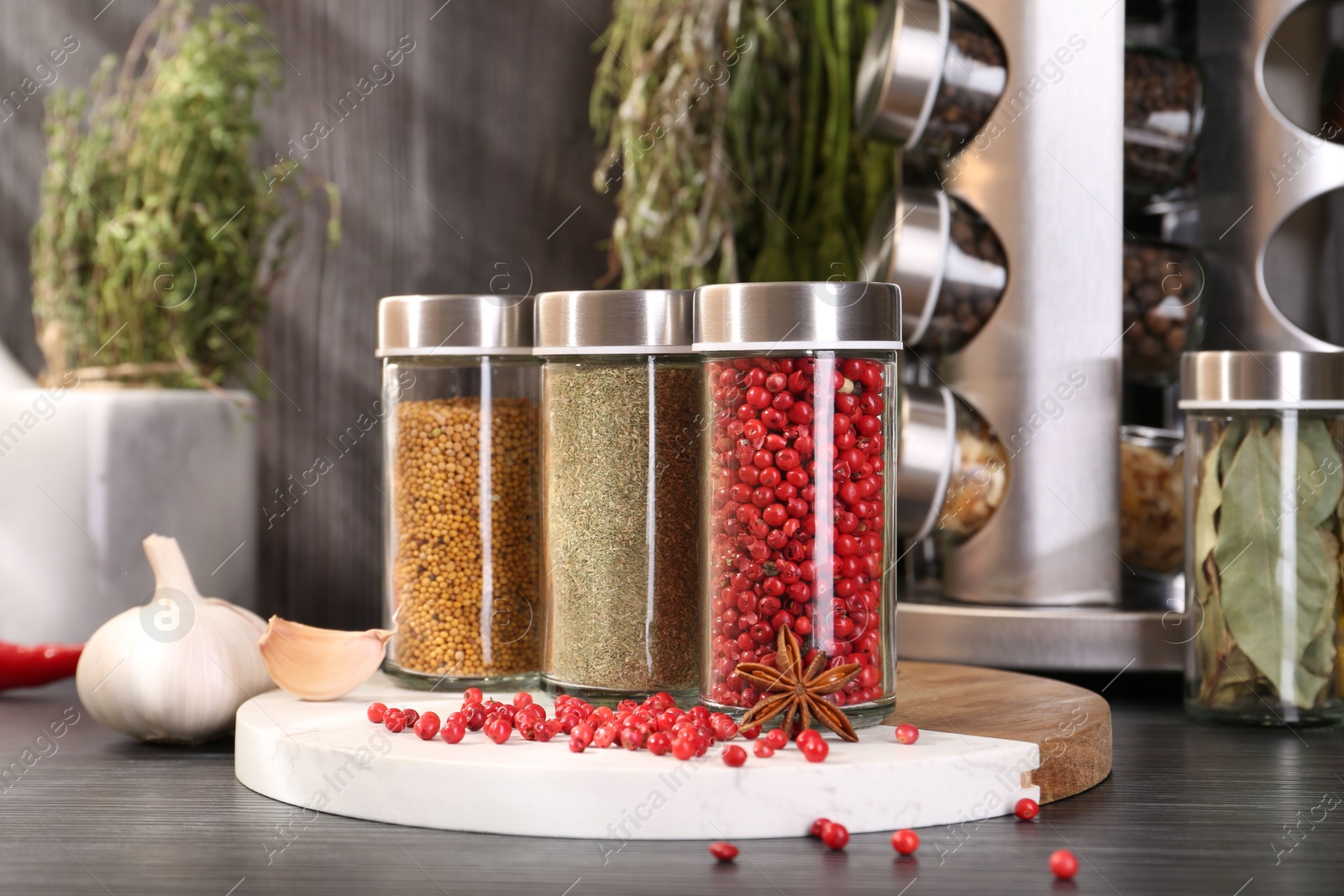 Different spices and glass jars on grey wooden table, closeup Photo of Different spices and glass jars on grey wooden table, closeup