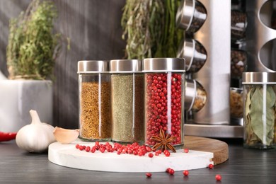 Photo of Different spices and glass jars on grey wooden table, closeup