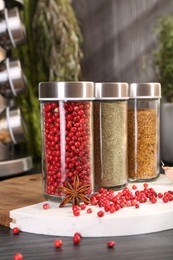 Photo of Different spices and glass jars on grey wooden table, closeup